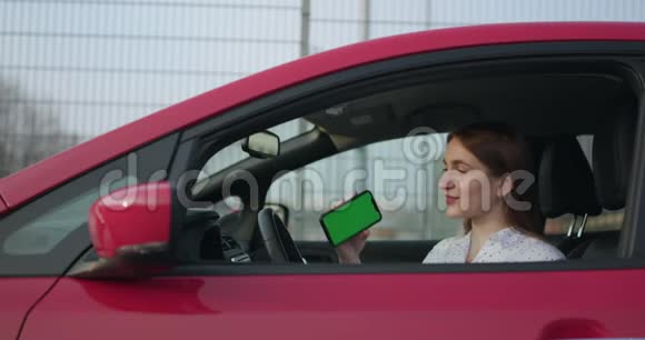女孩充电电动汽车和看应用程序在手机上关闭智能手机屏幕手持智能设备视频的预览图