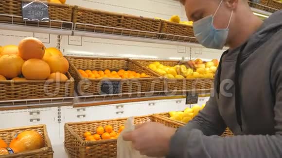 带医疗面罩的人在商店里挑选曼达林男人在超市里选择水果购买农产品视频的预览图