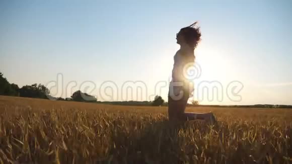 无法辨认的女人穿着白色连衣裙在日落时带着黄色的小麦穿过田野年轻无忧无虑的女孩视频的预览图