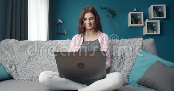 微笑的女人在家里用电脑消磨时间视频的预览图