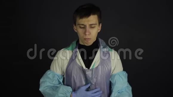 一个穿着防护服的年轻人咳出了冠状病毒模型样本孤立的黑色暗底视频的预览图