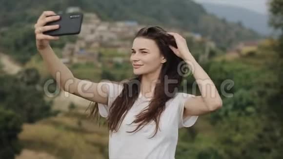 一个年轻苗条的白种人女孩长着棕色的头发在尼泊尔的一座山顶上自拍景观视频的预览图