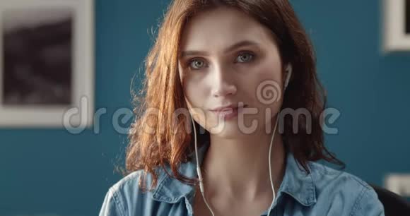坐在家里用耳机听歌的漂亮女孩视频的预览图