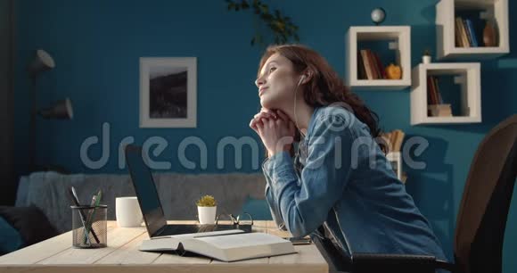 漂亮的年轻女孩坐在书桌上手提电脑和书视频的预览图