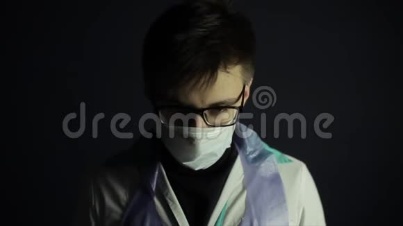 一个白人年轻人戴着医疗保护面具黑色深色背景衣服冠状病毒保护视频的预览图