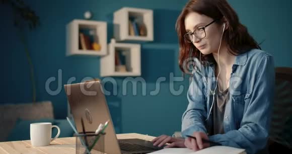 带眼镜的年轻女孩在家学习用笔记本电脑视频的预览图