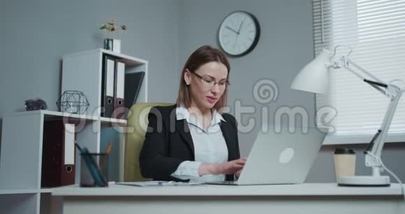 快乐的女人用笔记本电脑做网上银行微笑着用笔记本电脑上的在线应用支付账单视频的预览图