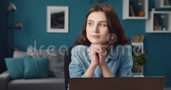 坐在桌边拿着笔记本电脑做梦的漂亮女孩视频的预览图