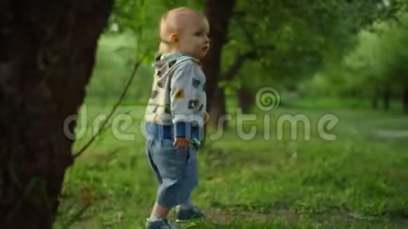 小孩抬头看着飞行球有趣的幼儿在绿色森林里散步视频的预览图