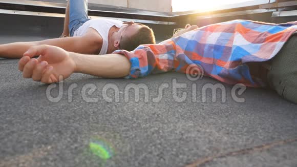 两个年轻人躺在屋顶上背景阳光明媚男人一起休息和享受生活朋友视频的预览图