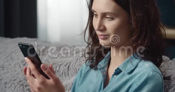 漂亮的黑发女人看手机屏幕视频的预览图