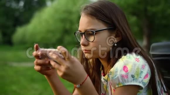 在绿色森林里严肃的少女在手机上发短信视频的预览图