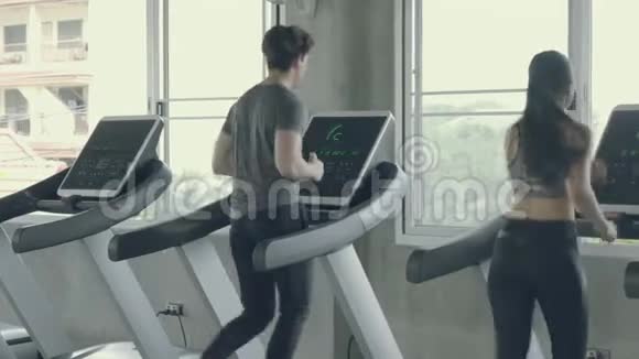亚洲青年男子和妇女在运动健身房里用跑步机进行有氧运动训练视频的预览图