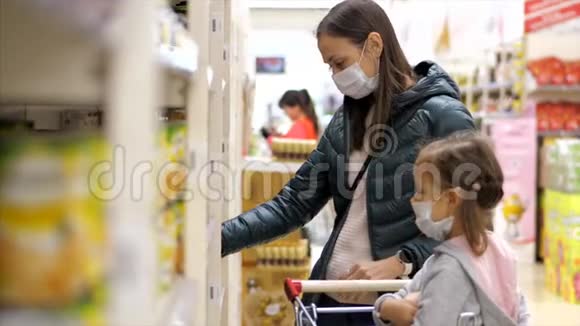 带着带口罩的女孩子的年轻女子在超市买罐头食品视频的预览图