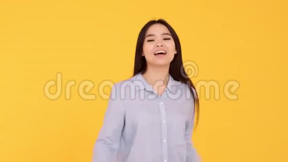年轻的亚洲女孩在黄色背景上展示手势课和微笑视频的预览图