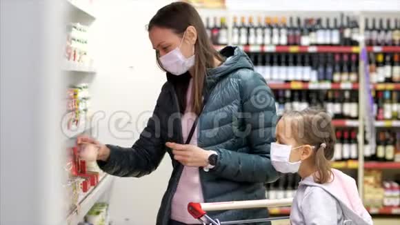 带着带着口罩的小女孩的年轻女子在超市买了一家奶制品视频的预览图