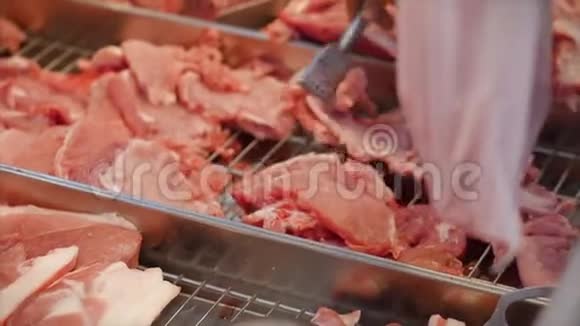 女人买肉看着鸡肉上的肉片在市场上在超市里用钳子夹肉视频的预览图