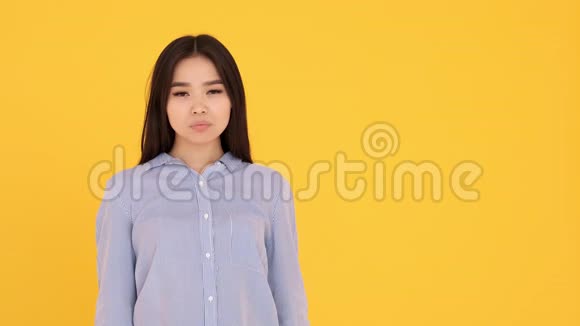 年轻的亚洲女孩对着镜头微笑复制空间黄色背景视频的预览图