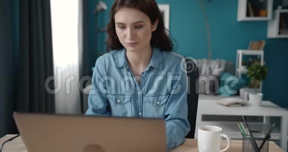 漂亮的女孩坐在办公桌前在笔记本电脑上打字视频的预览图