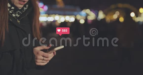 女人的手使用手机在城市的夜晚年轻女性发短信在手机户外交流社会视频的预览图