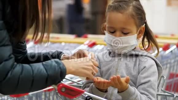儿童戴防护面罩在杂货店用消毒器消毒双手视频的预览图