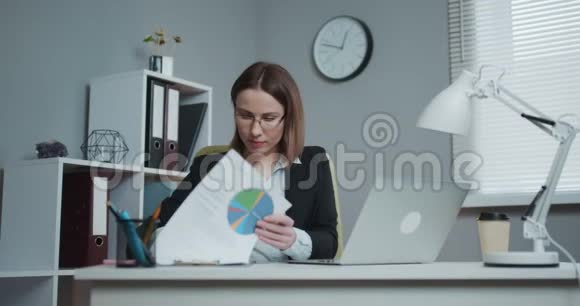 商务女性坐在办公桌上手里拿着一支笔拿着文件签合同视频的预览图