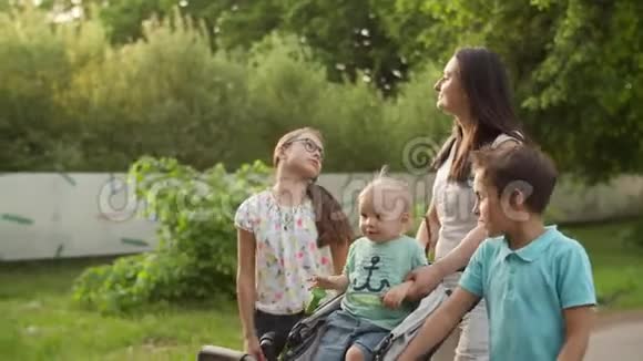放松的母亲带着三个孩子散步快乐的家庭在夏日公园放松视频的预览图