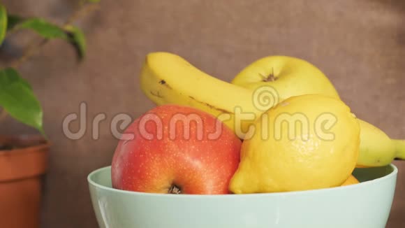 女人的手从厨房桌子上的盘子里轮流拿水果一个女孩摘香蕉柠檬苹果h视频的预览图