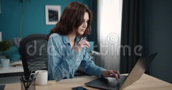 漂亮的女孩在家里用个人笔记本电脑视频的预览图