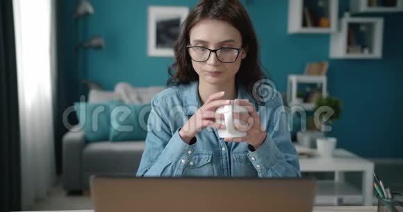 有魅力的女人喝着咖啡手提电脑视频的预览图
