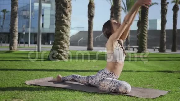 运动女孩在公园里伸展女人在草地上做瑜伽练习视频的预览图