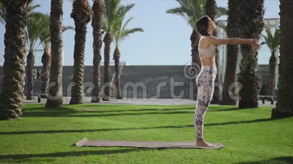 在公园里做棕榈树姿势的女人女孩在户外练习瑜伽视频的预览图