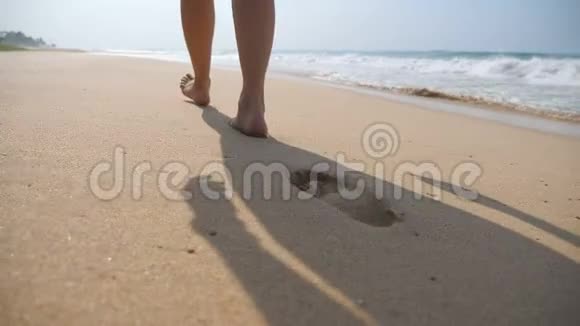 雌性的脚在沙滩上行走背景是海浪年轻女子踩沙的腿视频的预览图