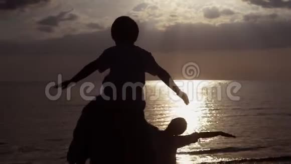 亚洲家庭幸福的剪影看日落在度假的时候在海滩上伸展双臂视频的预览图