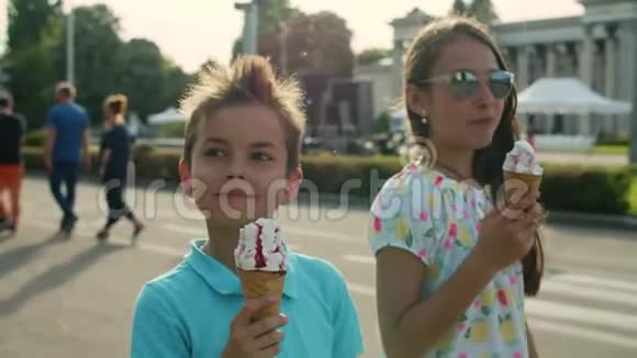 可爱的姐姐和哥哥吃冰淇淋微笑的孩子们在游乐园里散步视频的预览图