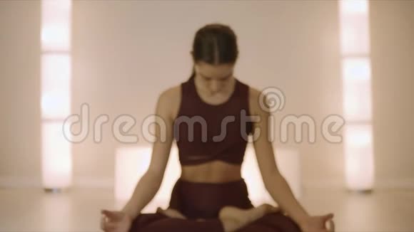 女人坐在瑜伽工作室的莲花姿势女子在室内冥想视频的预览图