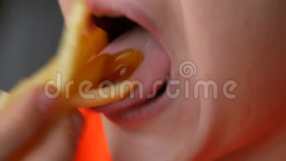 一个十几岁的男孩吃炸薯条加酱汁脸和嘴靠近视野不健康快餐视频的预览图