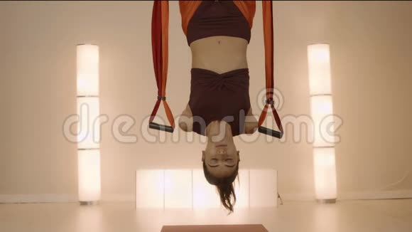女人倒挂在工作室的吊床上女孩练习反重力瑜伽视频的预览图