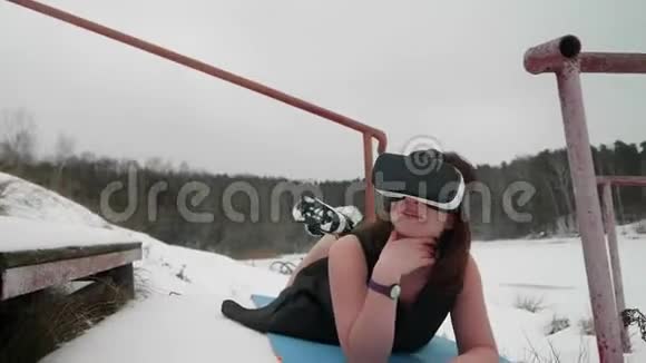 女人躺在蓝色运动地毯上戴着黑色夏装的VR眼镜她微笑着享受时光视频的预览图