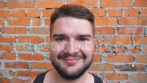 特写一个强壮的胡须男人看着相机把他的棕色头发理顺在户外年轻快乐的肖像视频的预览图