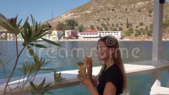 坐在海滨的漂亮女人拿着香蕉汁视频的预览图
