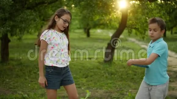 微笑的兄妹在户外跳舞夏季公园可爱的孩子视频的预览图