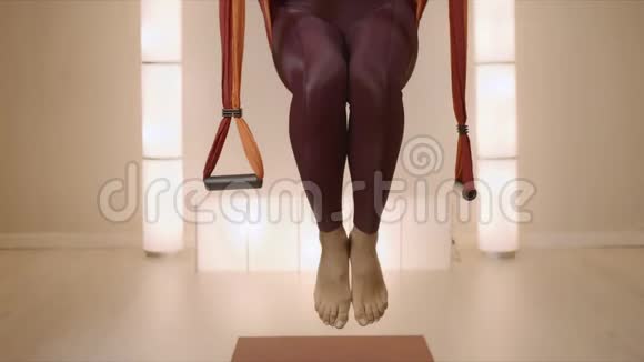 女士在课堂上把脚放在瑜伽带子里在吊床上做空中瑜伽的女人视频的预览图