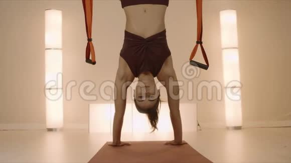 女运动员双手站在瑜伽课上吊床上倒吊的女孩视频的预览图