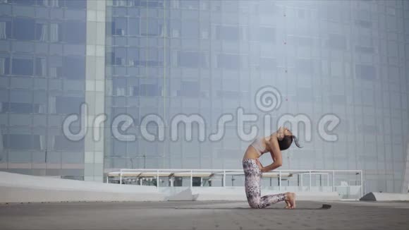 在街上做骆驼姿势的女人在城市大街伸展身体的女孩视频的预览图