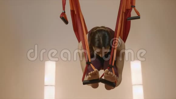 女孩在工作室练习反重力瑜伽女士在吊床上伸展身体视频的预览图