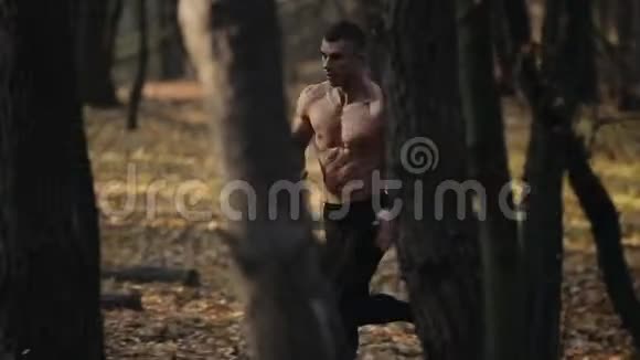 快速奔跑的肌肉男赤裸的躯干年轻的白种人在森林里跑步树上的风景视频的预览图