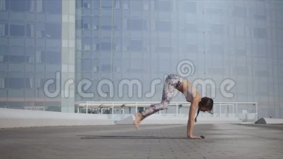 女孩做向上面对狗姿势户外在城市大街锻炼瑜伽的女人视频的预览图