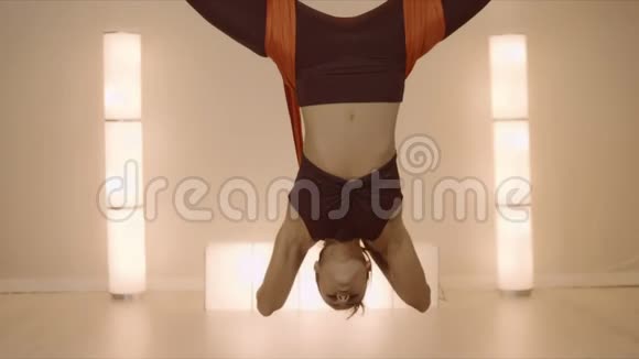 在吊床上练习蝴蝶倒立姿势的女人做反重力瑜伽的女士视频的预览图