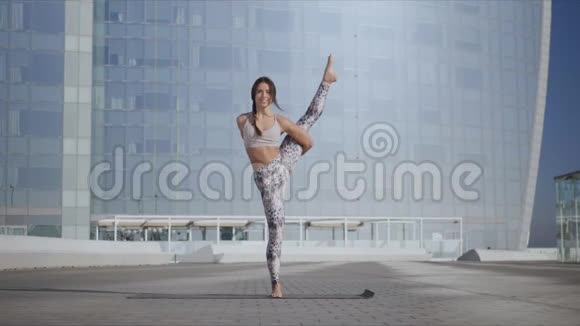 在城里做天堂鸟姿势的女人瑜伽教练单腿平衡视频的预览图